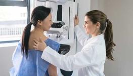 A doctor helps a patient get into position for a mammogram.